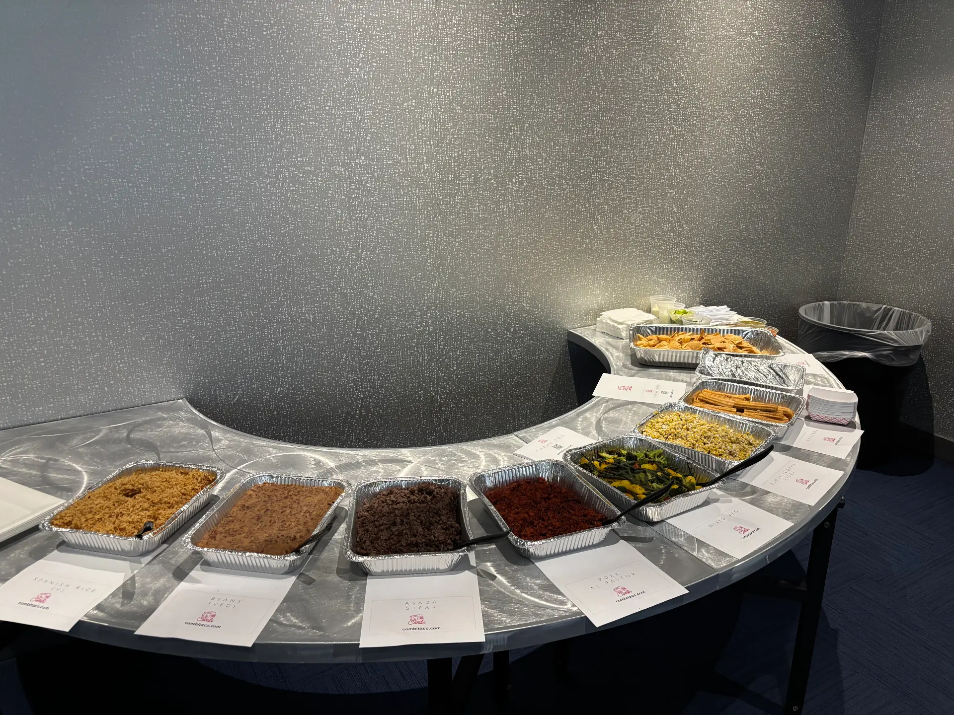 Curved buffet table with rice, beans, asada, al pastor and churros
