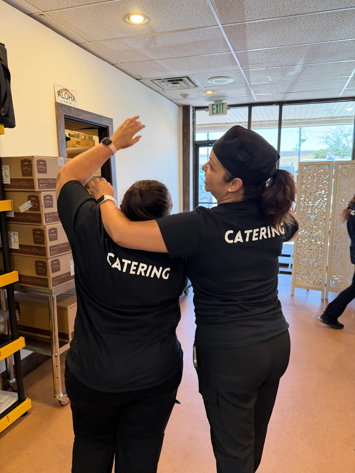Two Combi Taco catering staff in branded shirts working in the production kitchen