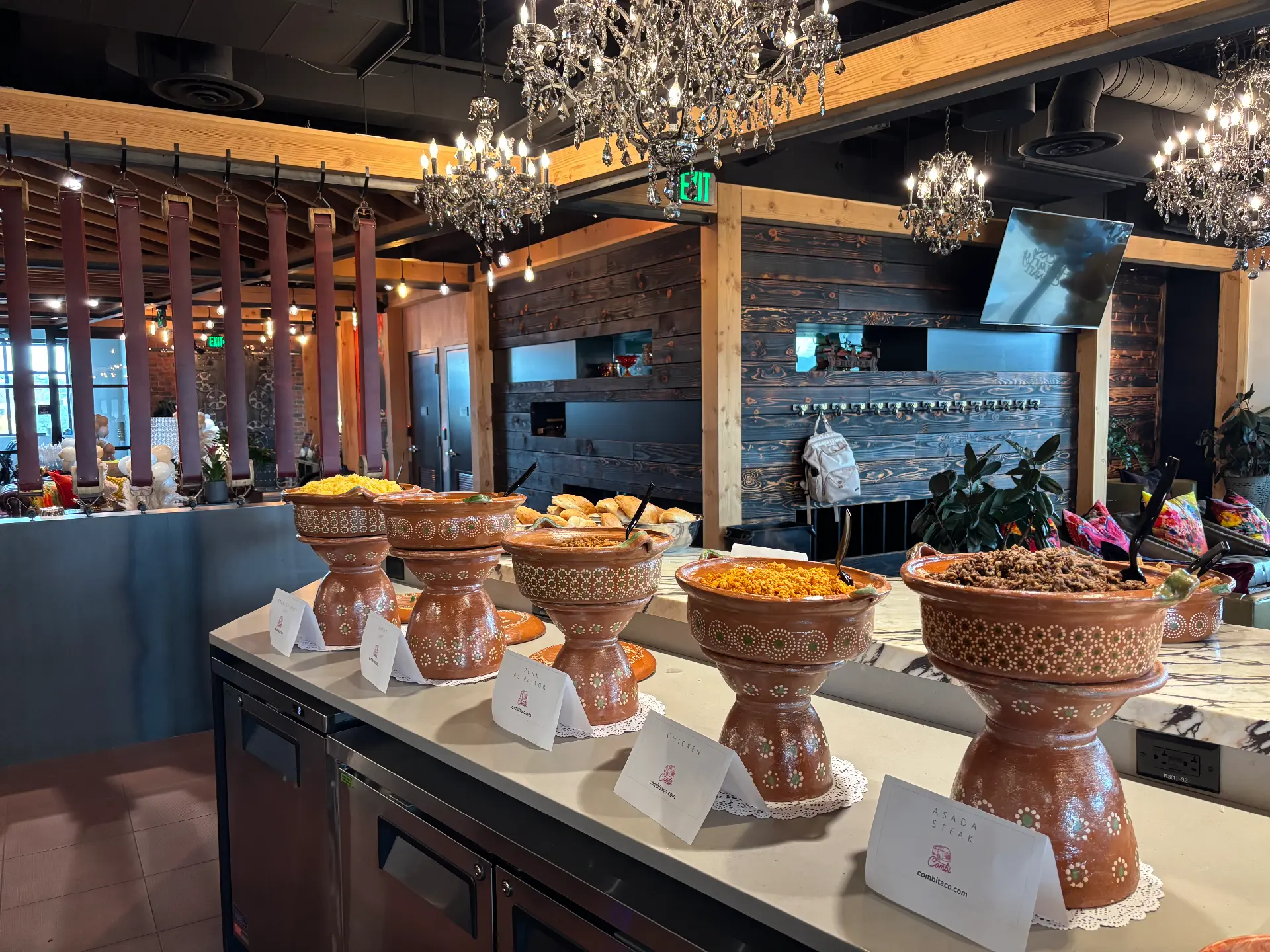 Clay pot taco bar under chandeliers with printed menu cards