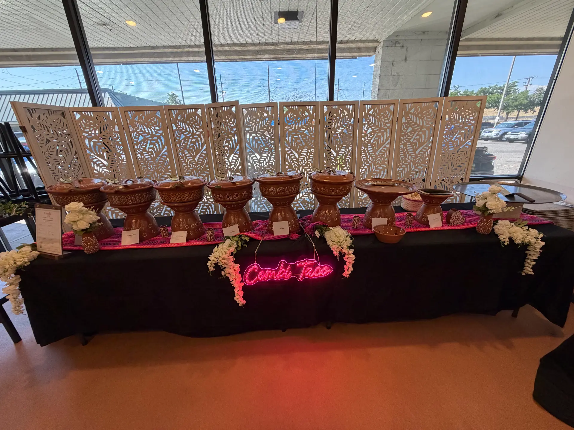 Catering table with clay pots and a pink Combi Taco neon sign