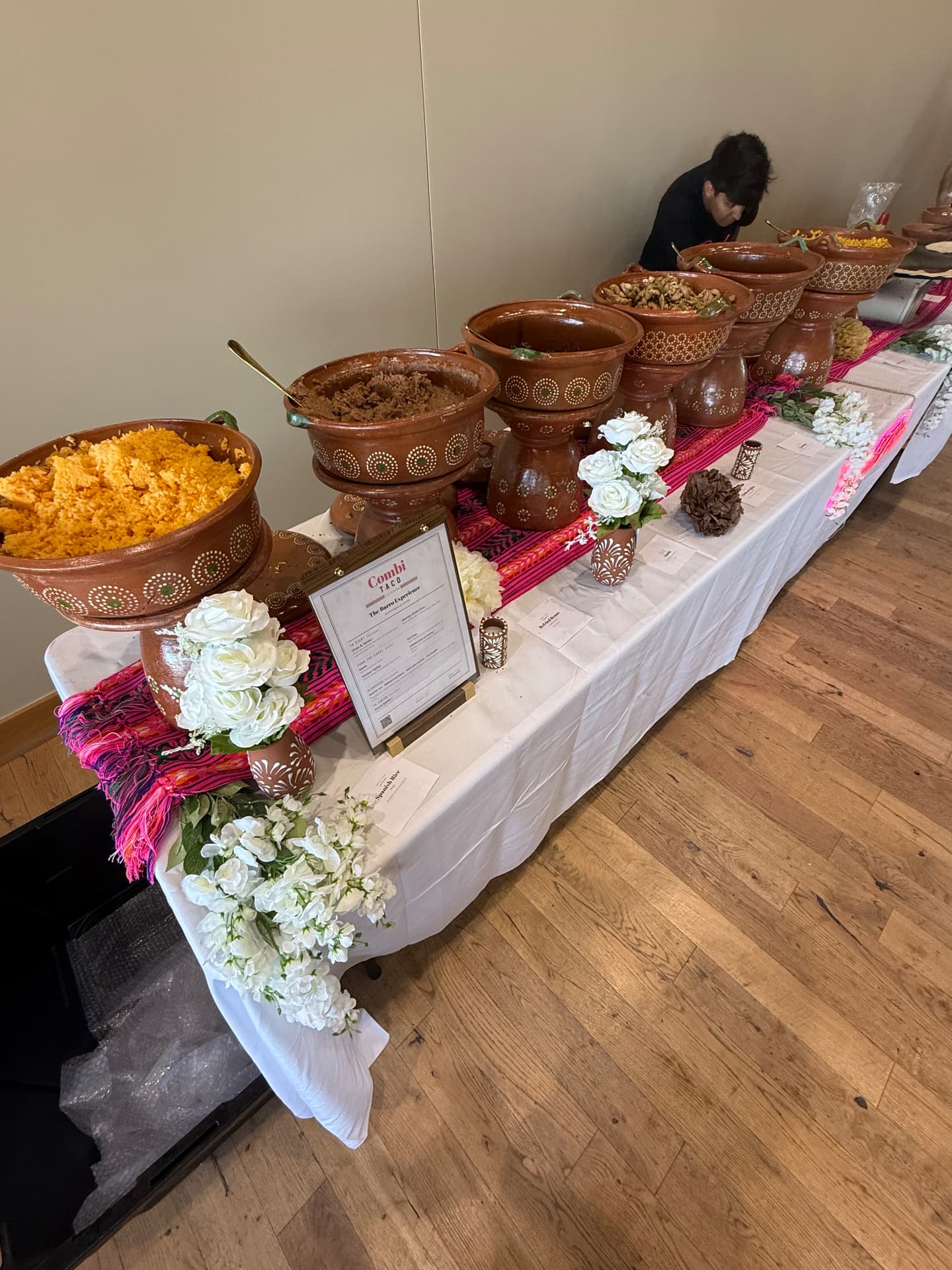 Wedding taco bar with white florals and pink textile runner